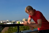 Romain. Consultant high-tech. Sur son balcon, quartier Sans Souci. D'ici la vue porte loin dans l'espace, dans le temps. Il suffit d'être à l'affût, disposer du bon matériel, des bons complices...