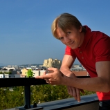 Romain. Consultant high-tech. Sur son balcon, quartier Sans Souci. D'ici la vue porte loin dans l'espace, dans le temps. Il suffit d'être à l'affût, disposer du bon matériel, des bons complices...